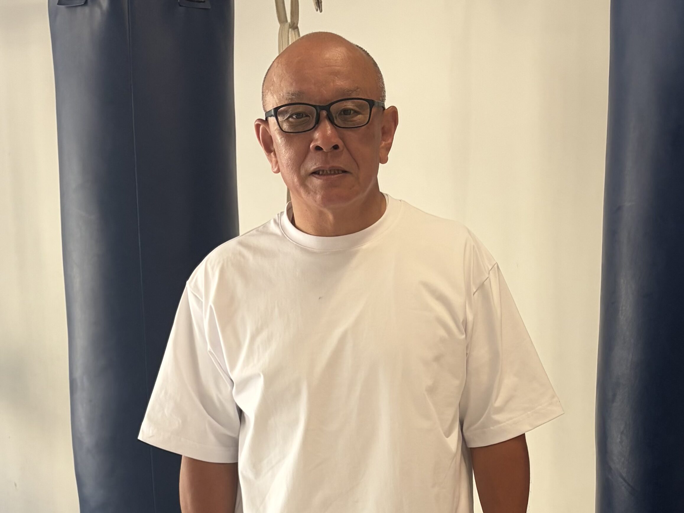 サンドバッグの前に立つ渡邉房光さん